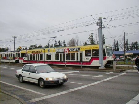 Light rail train in East Burnside St. approaches intersection and station at NE 181st. Ave. Photo: Adam Benjamin.
