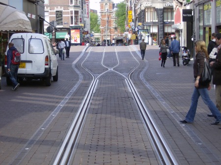Focus on interlaced track construction in the Leidsestraat. Notice how the two tracks  Notice how the two tracks virtually merge to form what almost seems like a single track — but there are separate parallel rails for each direction, laid next to each other. Also, only one rail in each direction actually cross each other (this type of passive, stationary rail crossing is called a frog).