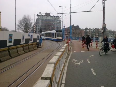 Interlaced track is also used in other narrow locations, some shared with motor vehicle traffic. Here a Route 10 tram leaves the interlaced track over the Hoge Sluis bridge, as an autombile waits to proceed over the same right-of-way.