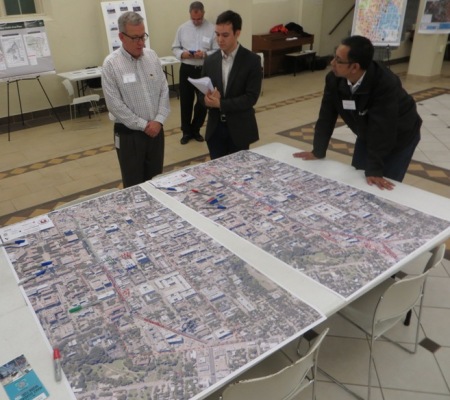 At Dec. 3rd Guadalupe Transportation Corridor Project public event, project manager Alan Hughes (center, in checkered shirt) discusses project issues over table with Drag corridor maps. At far right in photo is Roberto Gonzalez of Capital Metro's Planning Department. Photo: L. Henry.