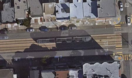 Aerial view of Judah St. corridor segment, showing central reservation with Muni Metro LRT train, motor vehicle lanes on each side, and sidewalks on each side of arterial. Photo: Google Maps Satellite View.