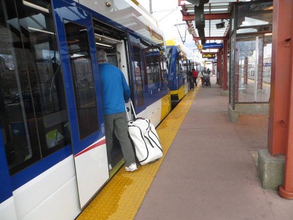 Traveler with baggage boards Blue Line train at downtown station. With level boarding (station platform level with car floor), carrying on luggage is easy. Photo: L. Henry.